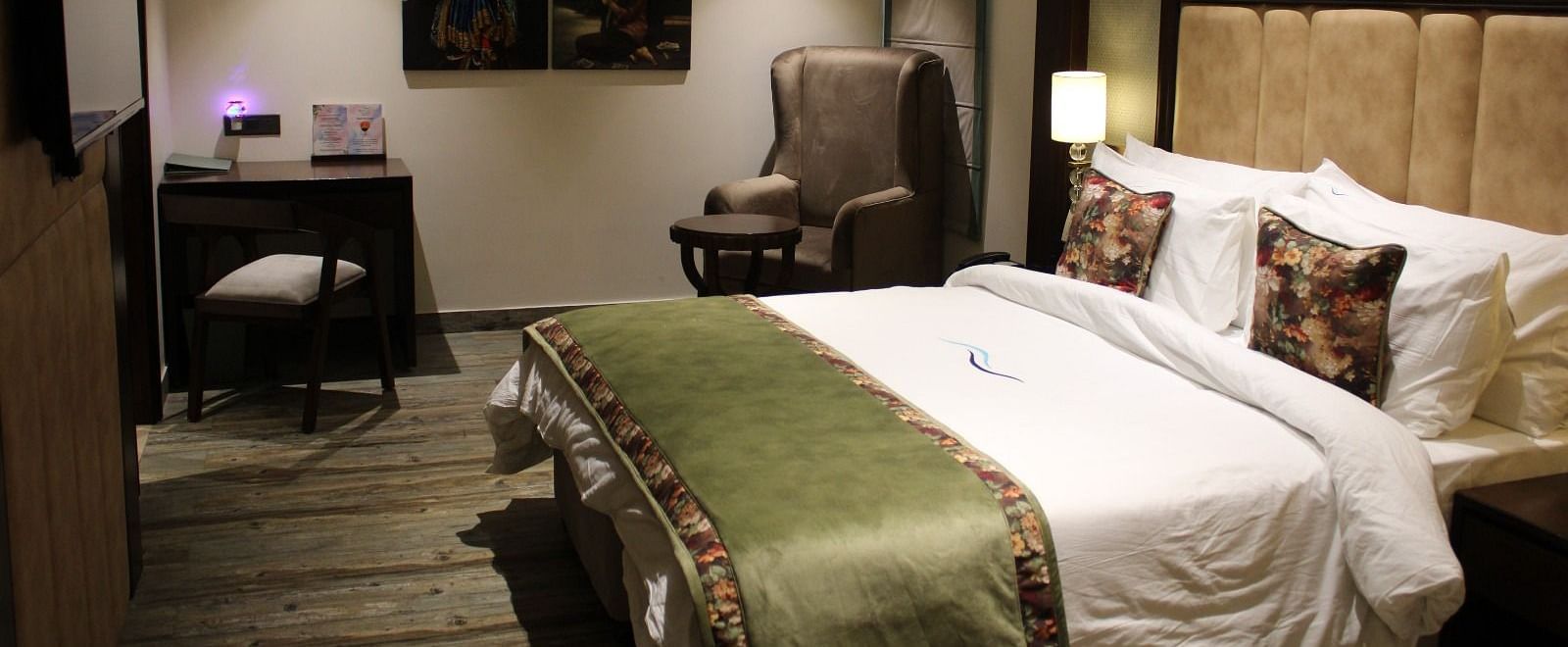 Side view of a bedroom featuring a working table, a chair, and portraits adorning the wall at BluSalzz Residence, Amritsar